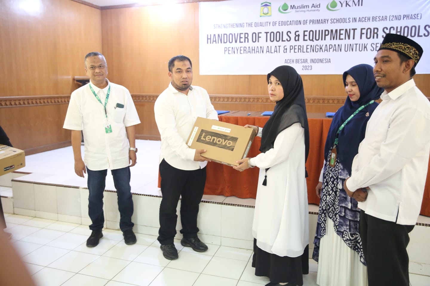 Pj Bupati Aceh Besar Muhammad Iswanto SSTP, MM didampingi Plt Kadisdikbud Aceh Besar Agus Jumaidi SPd MPd menyerahkan sejumlah bantuan alat dan perlengkapan sekolah kepada kepala sekolah dari YKMI di Aula Balai Guru Penggerak (BGP), Kecamatan Ingin Jaya, Aceh Besar, Rabu (17/05/2023). [FOTO/ HO Habanusantara]