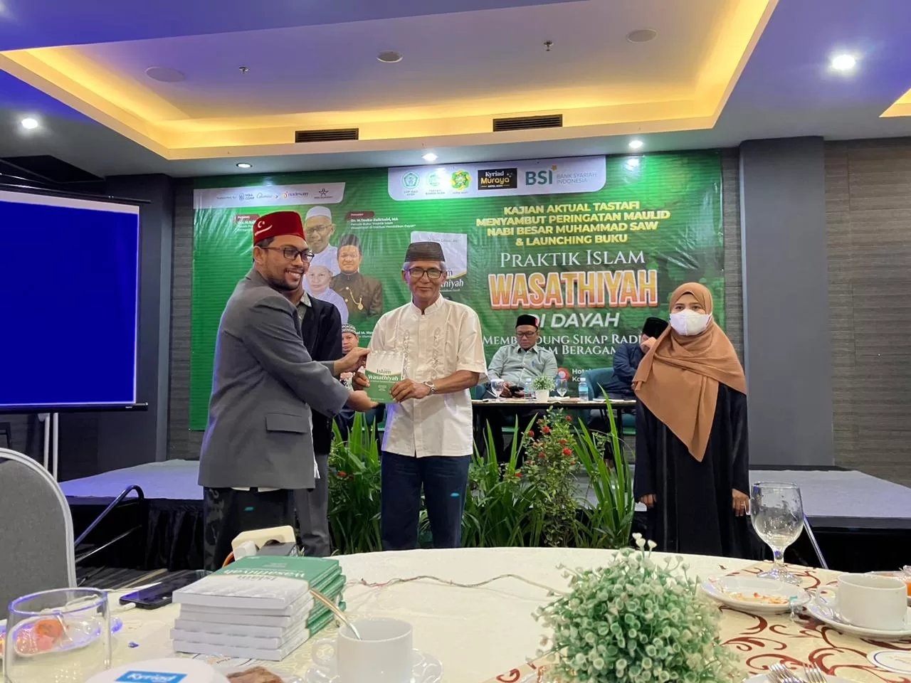 Tgk Mustafa Husen Woyla, S.Pd.I, Ketum DPP ISAD Aceh menyerahkan buku setelah diluncurkan kepada salah satu peserta di Kyriad Hotel Banda Aceh, Rabu 27 September 2023 malam [Foto/HO For Habanusantara]