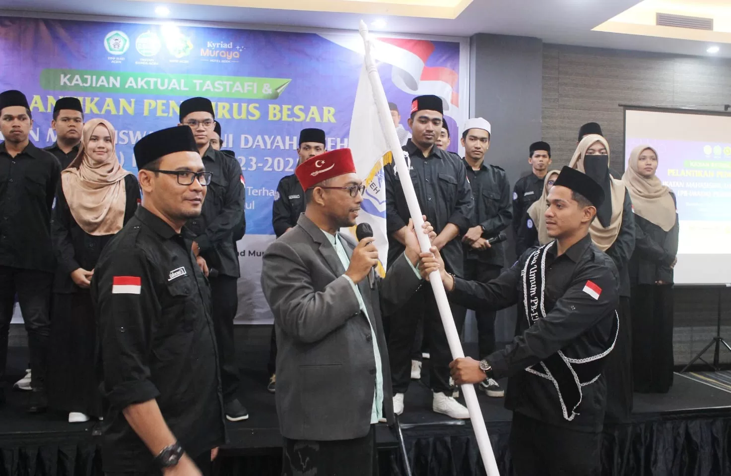 Tgk Tabrani menyerahkan Pataka IMADA kepada Tgk Mustafa Husen Woyla untuk diserahkan kepada ketua umum terlantik, Tgk Rozy Munawir sekaligus penekanan mandat secara lisan untuk dikibarkan seluruh Aceh (7/12/23), Kyriad Muraya Hotel, Banda Aceh
