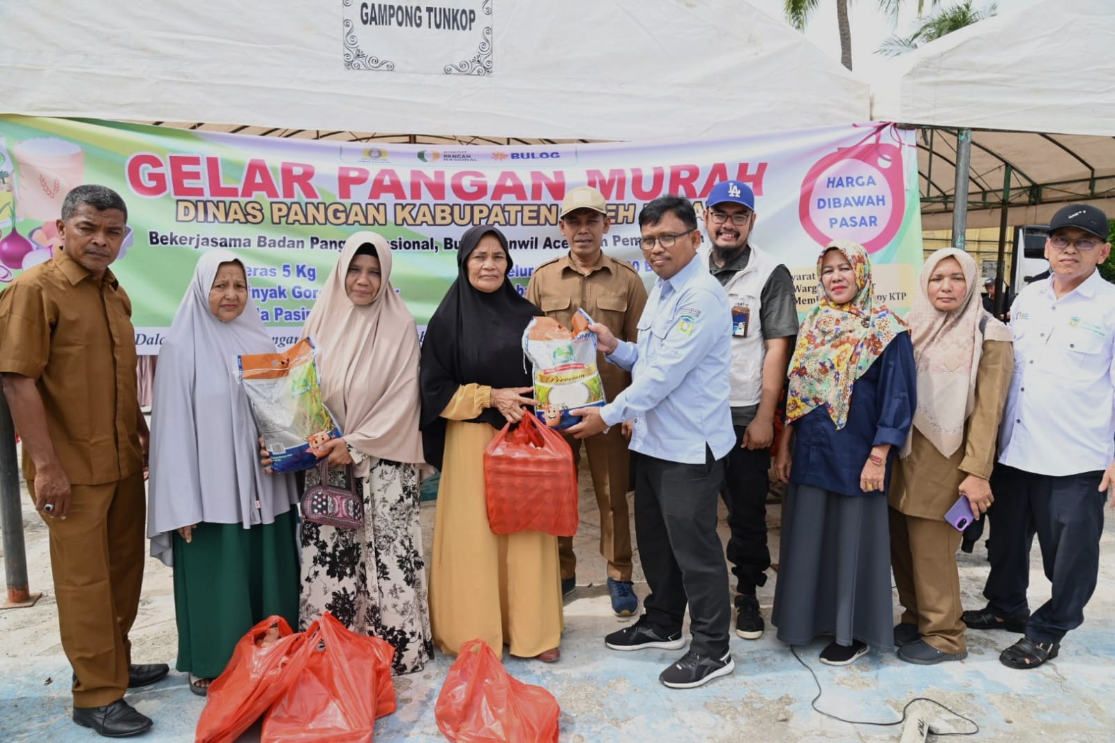 Kadis Pangan Aceh Besar, Alyadi,S.Pi, MM bersama Forkopimcam Darussalam menyerahkan sembako murah secara simbolis saat gelar Pasar Murah di Halaman Meunasah Tungkop, Kecamatan Darussalam, Aceh Besar, Selasa (21/05/2024). FOTO/MC ACEH BESAR